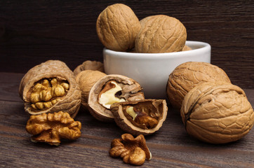Handful of Walnuts in white bowl on wooden background