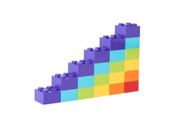 Fototapeta premium Colorful rainbow colored ascending stacks made of toy building bricks, isolated on white background.