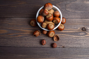 Filbert nuts in white porcelain bowl on wooden background