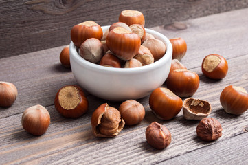 Filbert nuts in white porcelain bowl on wooden background