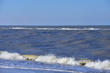 Morska fala z pianą atakuje piaszczystą plażę. - obrazy, fototapety, plakaty