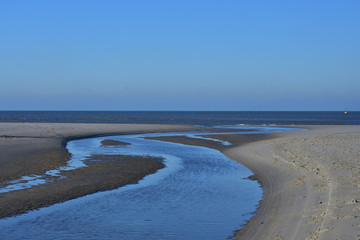 Piaszczysta plaża podczas odpływu pod bezchmurnym niebieskim niebem.