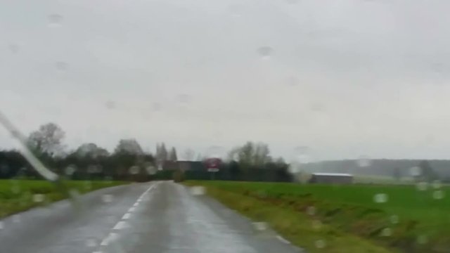 Slow motion interior vehicle point of view footage while driving in the rain in a rural area of France.