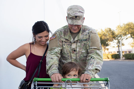 Soldier helping his daughter push a shopping cart