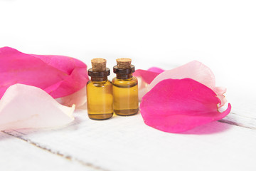 Essential oil with rose petals on wooden background with copyspace. Aromatherapy spa herbal products