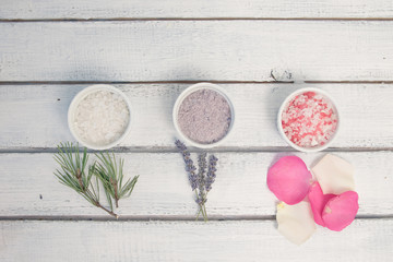 Aromas of bath salt. Rose, lavender and pine near bowls with colorful bath salt on light wooden background top view copy space