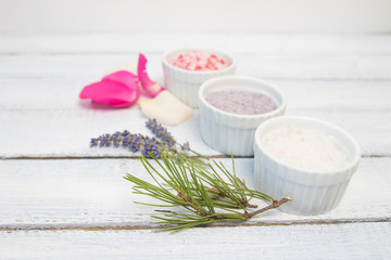 Obraz na płótnie Canvas Aromas of bath salt. Rose, lavender and pine near bowls with colorful bath salt on light wooden background top view copy space