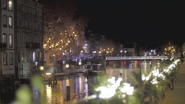 Picturesque view of traditional Alsatian half-timbered houses, bridge, Illriver with mirror reflections and cristmas decoration during night in Strasbourg, Alsace, France.