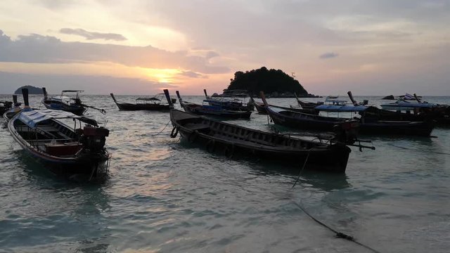 Group of Thai traditional longtail boats on white sand beach at Sunrise beach during sunrise time, Lipe Island, Thailand.