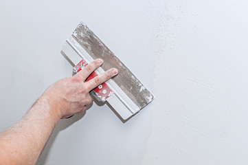 Hand with trowel, repair wall, Trowel with putty structure, the process of applying a layer of...