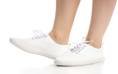 Naklejka premium Female legs in white sneakers shoes beauty on white background. Isolation