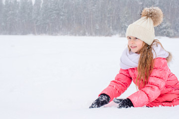 Portrait of little adorable girl in snow sunny winter day