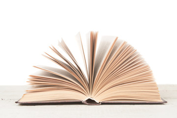 Open book on wooden desk on white background