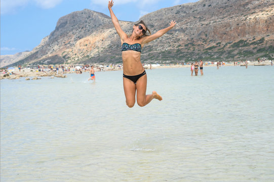 Happy smiling young woman is jumping on the beach. Concept of friendly family. Happy summer days. Balos Lagoon. Elafonisi Beach - Crete, Greece. - Image
