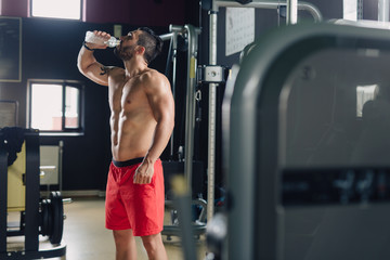 Strong man in the gym drinking water