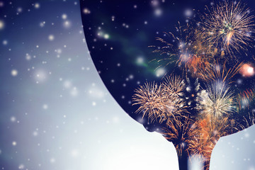 Colorful fireworks against the black silhouette of a wine glass with falling snow background.