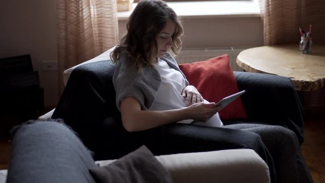Pregnant woman watching media content on digital tablet