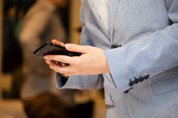 The hands of a young man who dials a phone number on a black smartphone 