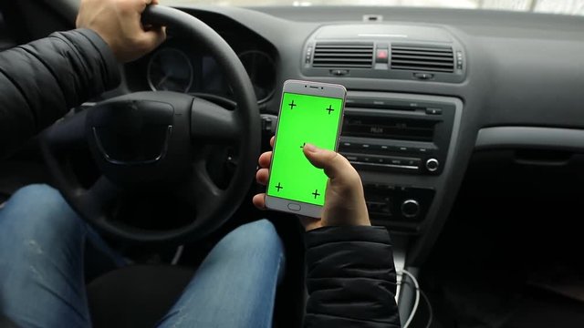 Man holding empty green screen of smartphone in car, chroma key
