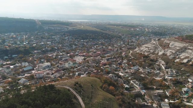A city in lowland near the cliffs covered by pines. Shot. Aerial view