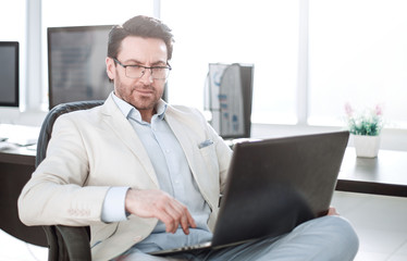 businessman using a laptop sitting at his Desk