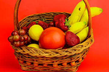 Vintage Wicker Basket filled with Assorted Fruits against Red BG