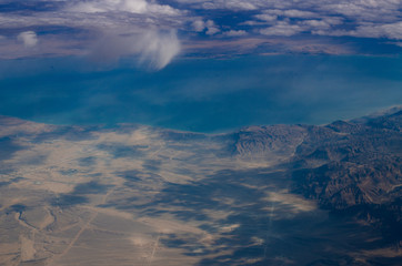Aerial view fluffy clouds above desert landscape and Suez Gulf in Egypt. Airplane view background