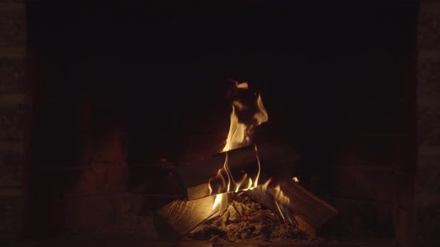 Flames dance over a split log. 4k Ultra HD loopable video
