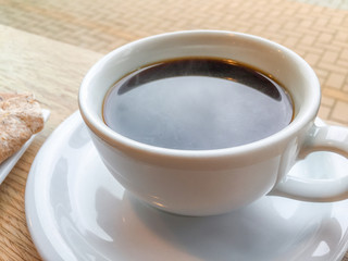 Black coffee in white ceramic cup and saucer in a cafe under even natural light.