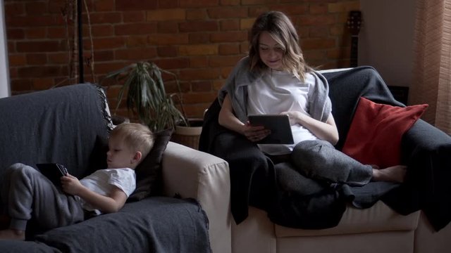 Pregnant mother and son using digital tablet at home