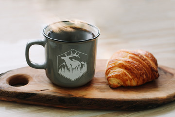 Mug of hot coffee and croissant on a wooden tray. breakfast concept. 