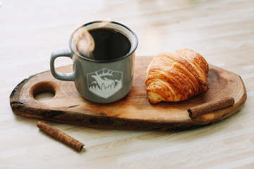 Mug of hot coffee and croissant on a wooden tray. breakfast concept. 