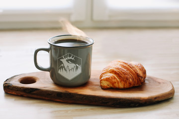 Mug of hot coffee and croissant on a wooden tray. breakfast concept. 