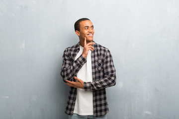 Obraz premium Young african american man with checkered shirt thinking an idea while looking up