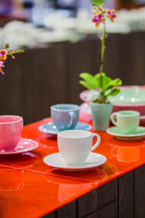 Tea set, porcelain mugs of different colors, decorated table for tea drinking