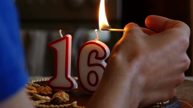 Hand lighting a Sixteenth Birthday cake with numerical candles