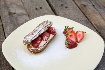 Strawberry eclair white plate on wooden background
