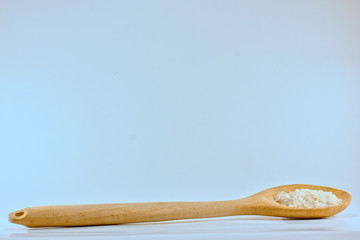 a wooden spoon with some rice grains isolated on white with some copyspace