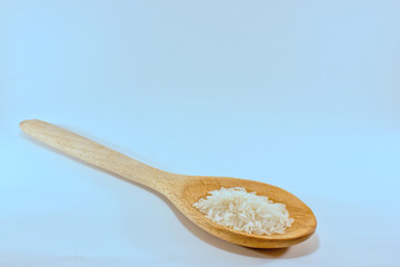 a wooden spoon with some rice grains isolated on white with some copyspace
