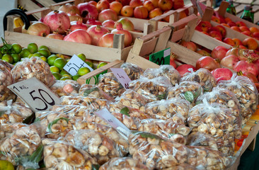 Packets of dried fig and ripe pomegranate in wooden boxes on a farm market counter