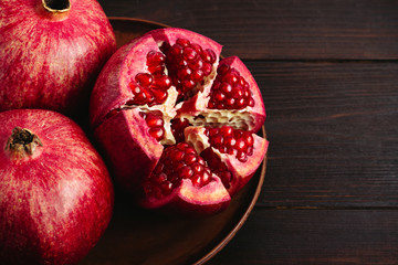 Cutted pomegranate in the plate on dark wooden background