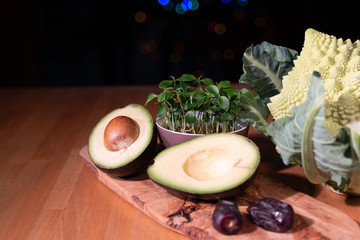 Half of the avocado and colored cabbage, other vegirables on the desk made from olive tree