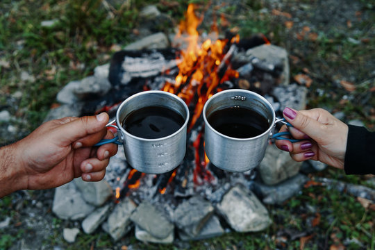Two cups of coffee at campfire in nature.