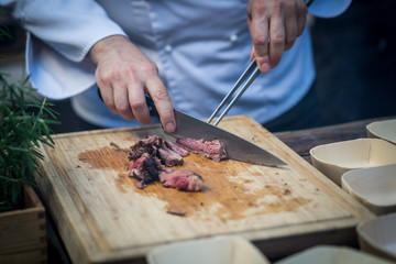 chef cutting meat with knife on cutting board
