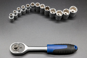 Set of tools - socket wrench with heads on gray background