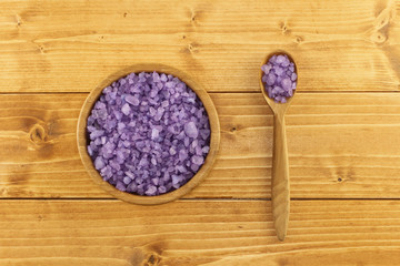 Lavender sea salt for bath in bamboo bowl on light brown wooden background    