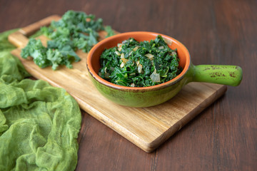 Fresh Kale and Onions in Terra Cotta Bowl on Wooden Tabletop; Fresh Kale in background