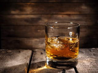 Whiskey glass with ice on wood