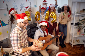 Smiling business workers have fun in Santa hat at Christmas party.