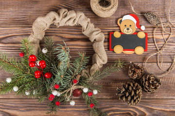 Wreath. Christmas winter frame on dark wooden background. Red elements, сhalk board with santa